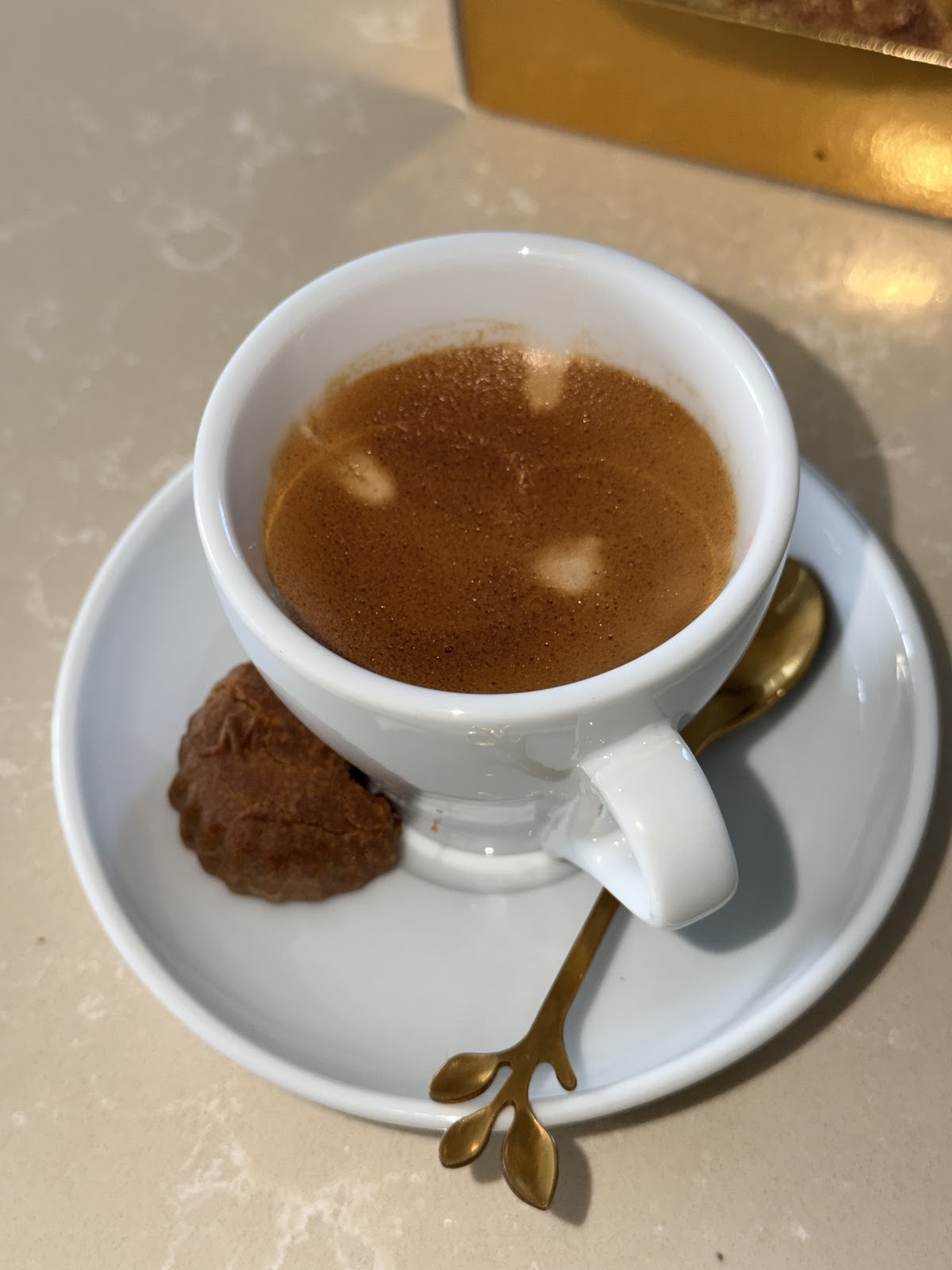 Espresso dans une tasse blanche avec cuillere doree et biscuit
